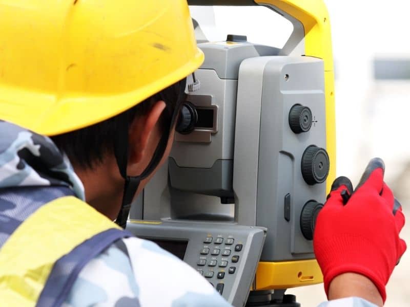 Surveyor using construction survey control equipment to guide public site layout checks and field alignment.